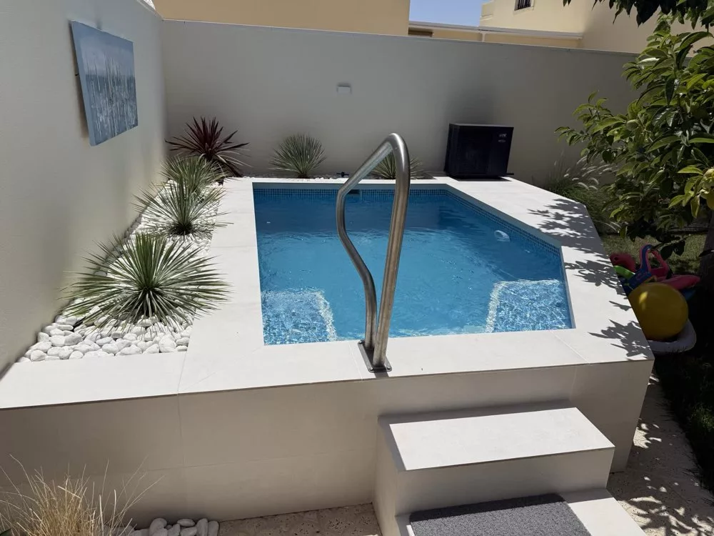 Above-ground pool with steel handrail in a walled garden, built by Creator Company in La Florida